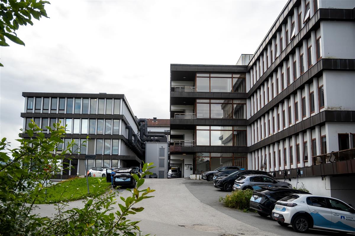 Utsiden av bygget i Sykehusveien 3A med tilhørende adkomstvei og parkeringsplasser. - Klikk for stort bilde